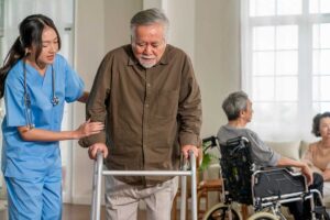 A senior resident using a handrail in a well-lit hallway with safety grab bars and slip-resistant flooring.